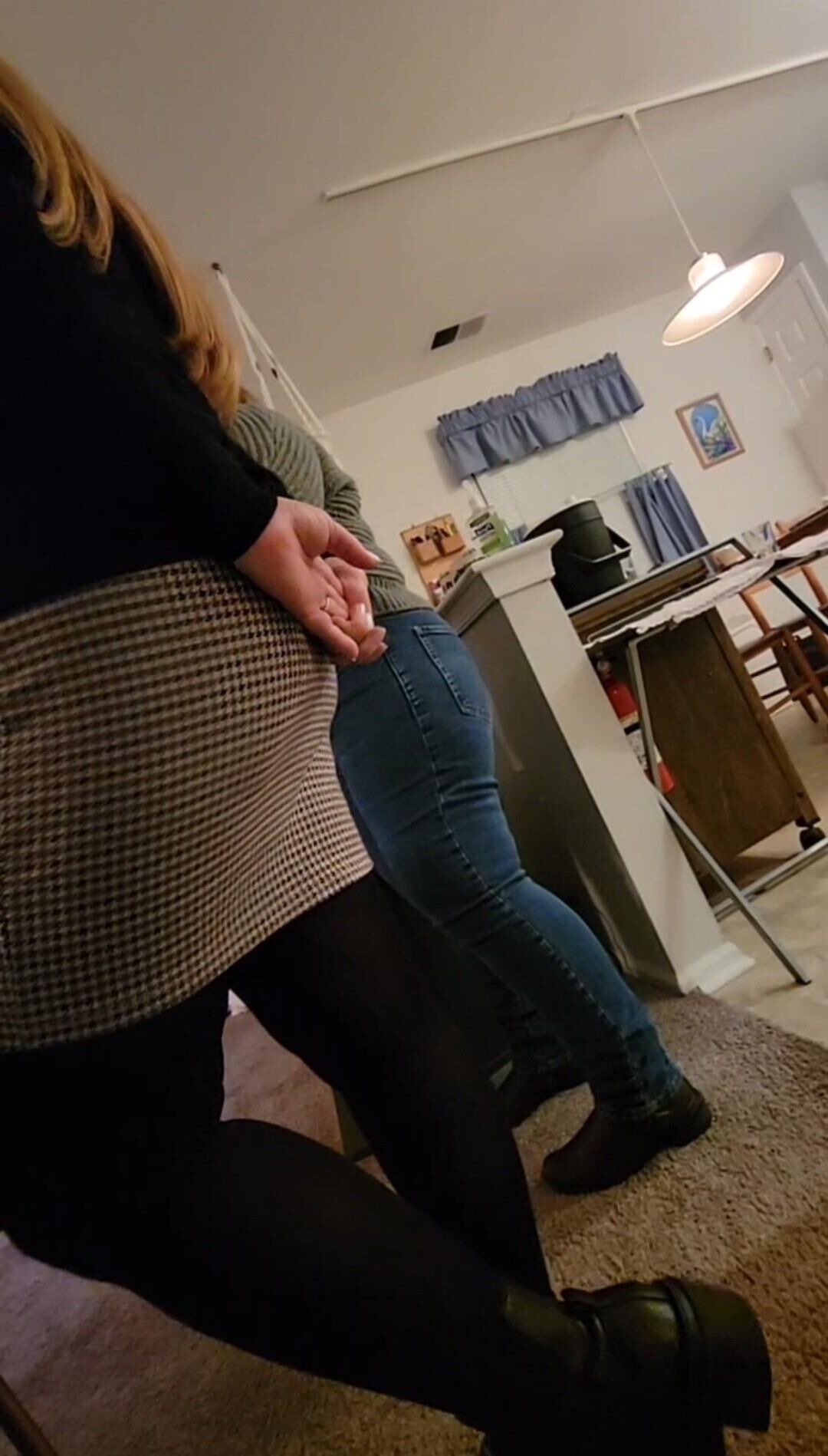 MILF blonde en minijupe, collants et bottes prépare le dîner