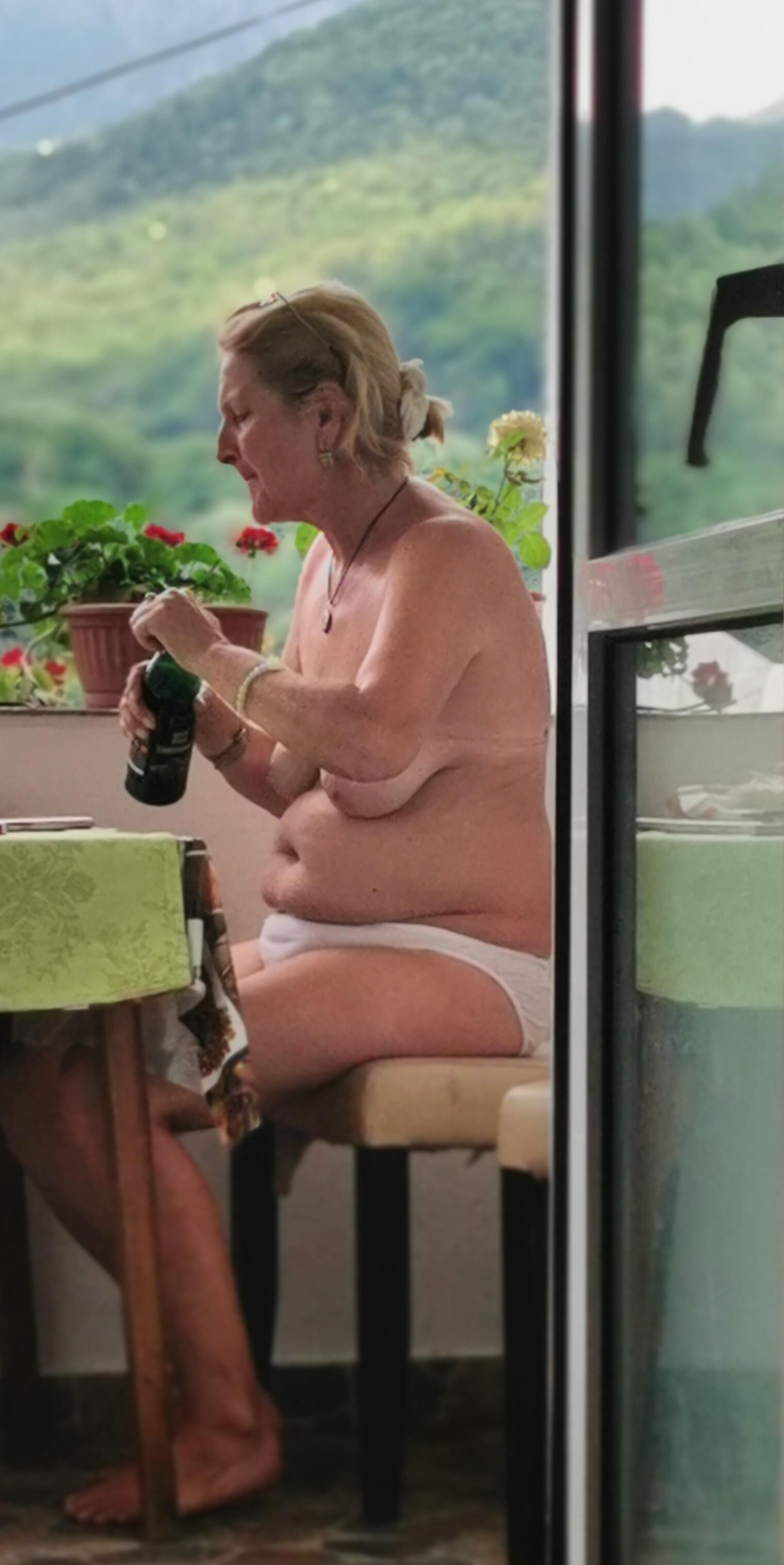 Antiga prostituta Maria de topless na varanda, para visualização pública