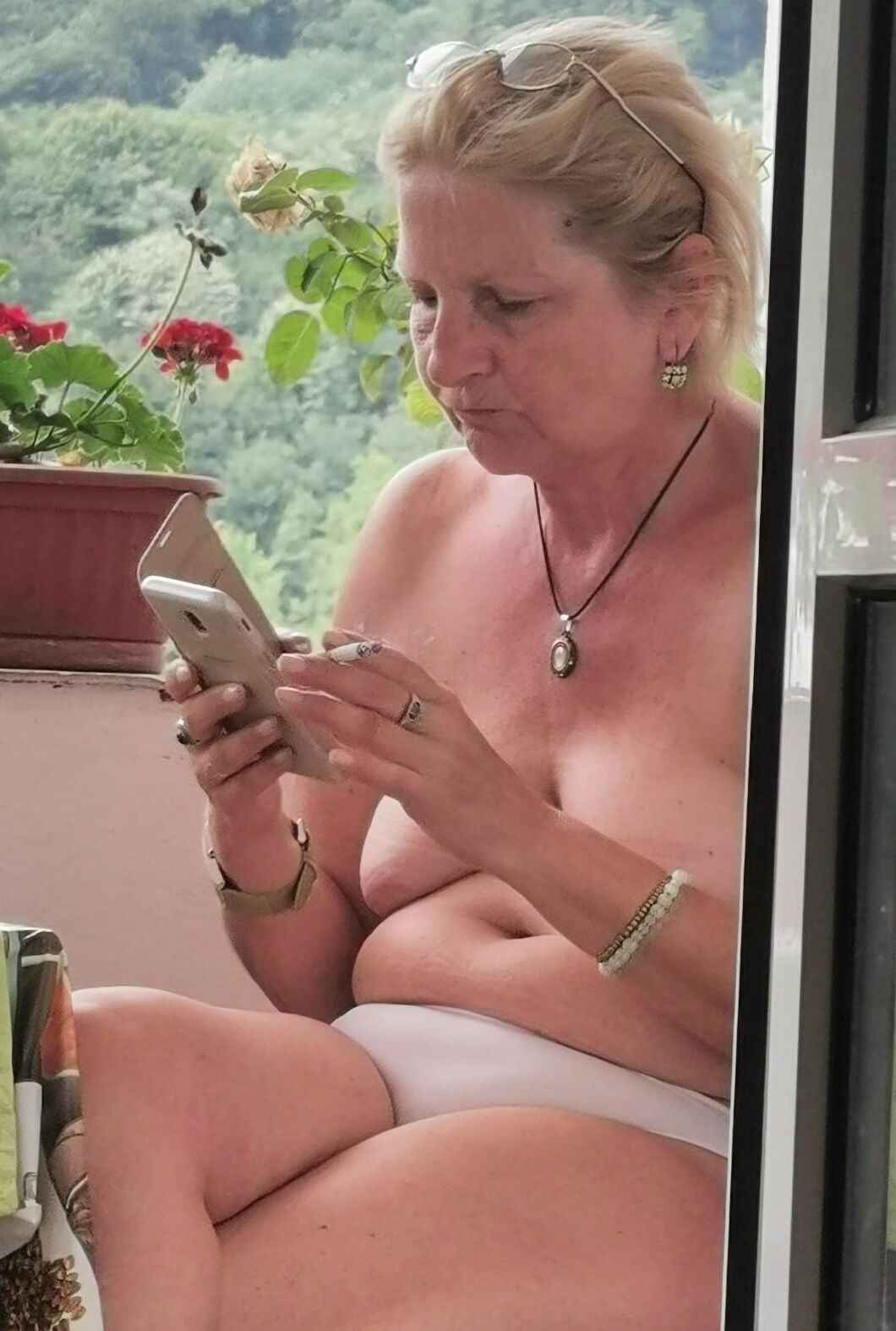 Antiga prostituta Maria de topless na varanda, para visualização pública