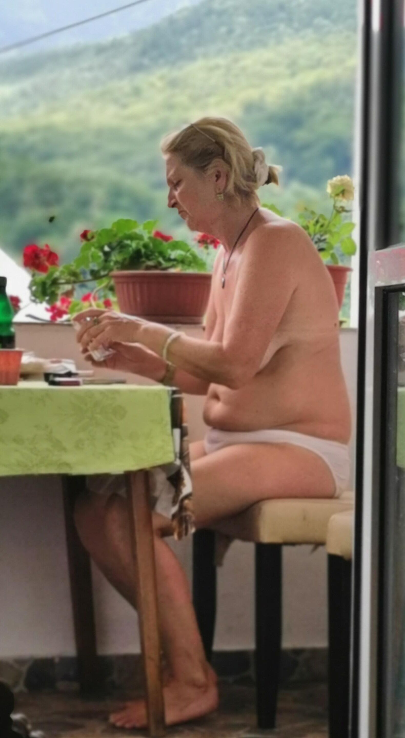 Antiga prostituta Maria de topless na varanda, para visualização pública