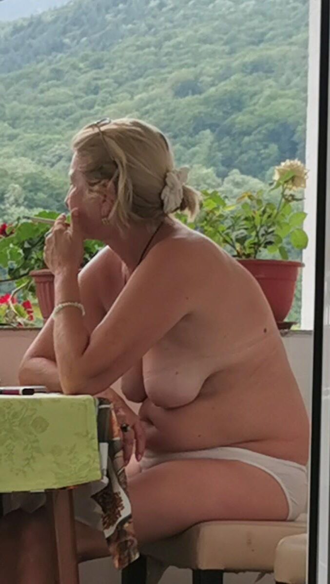 Antiga prostituta Maria de topless na varanda, para visualização pública